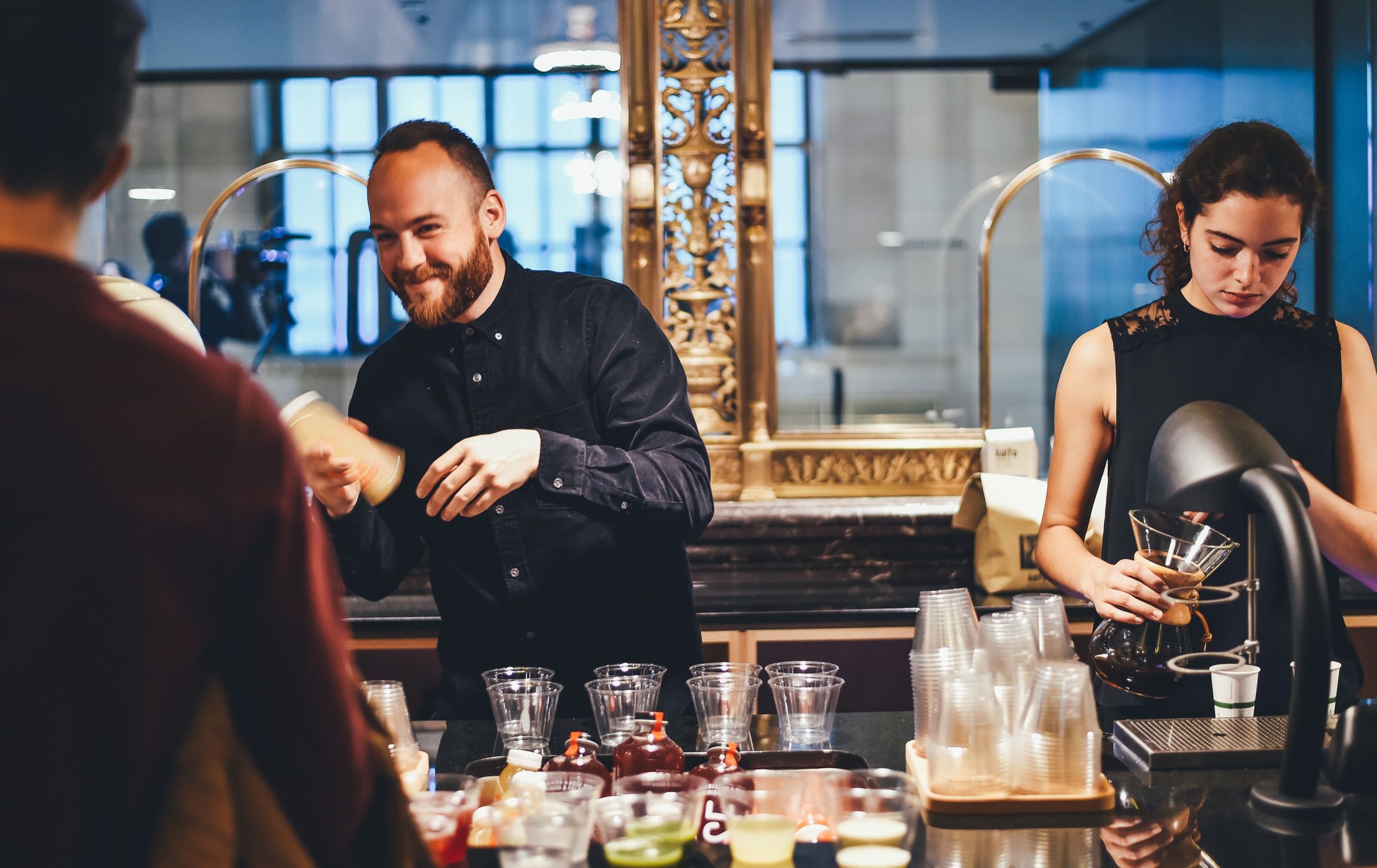 A bartender smiling as he serves a drink.