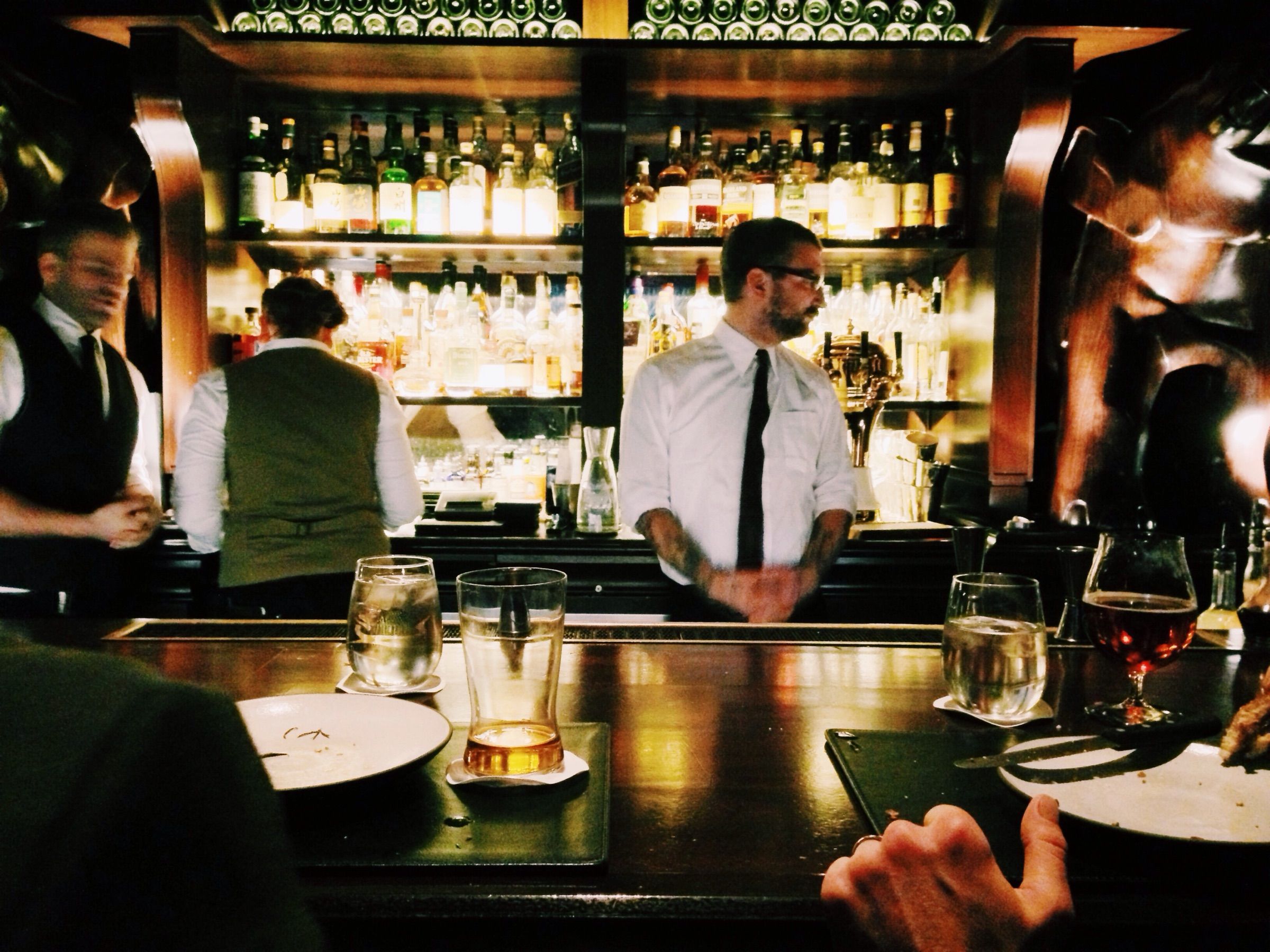 Two bartenders at work behind a busy bar.
