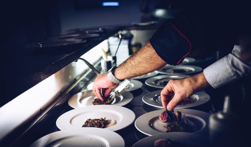 A chef plating dishes at the pass.